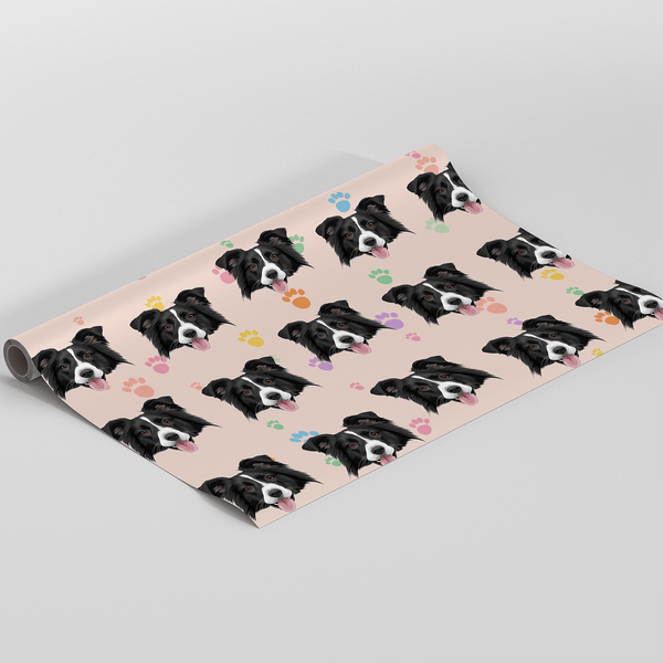 A roll of wrapping paper featuring a repeating pattern of black and white dog faces on a pale pink background, with small colorful heart and paw prints, shown on a white studio background.