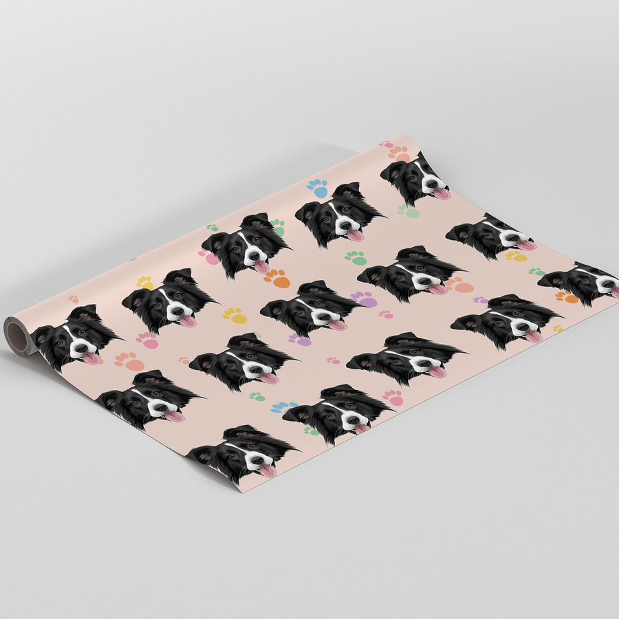 A roll of wrapping paper featuring a repeating pattern of black and white dog faces on a pale pink background, with small colorful heart and paw prints, shown on a white studio background.