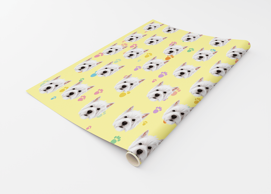 A roll of wrapping paper with a repeating pattern of white dog faces on a pale yellow background, accented with small pastel paw prints, shown on a white studio background.