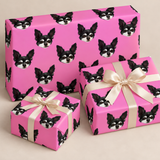 repeating black and white dog face on hot pink background wrapping paper with three presents and cream bow with a light grey background